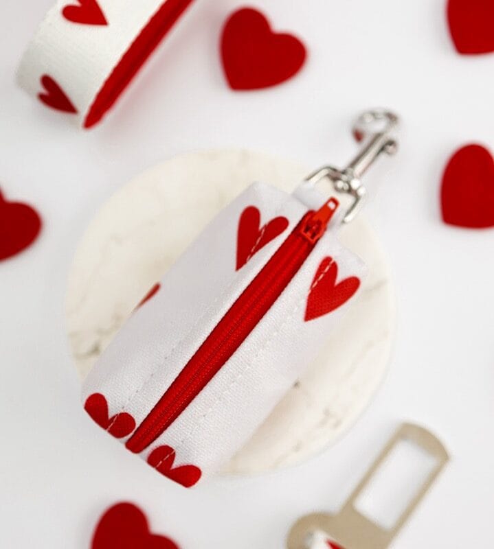 etui-na-worki-dla-psa-white-love-detal-serce Zbliżenie na spód białego etui na kupoworki White Love, pokazujące czerwony gumowy podajnik w kształcie serca i metkę z logo Puppmour.