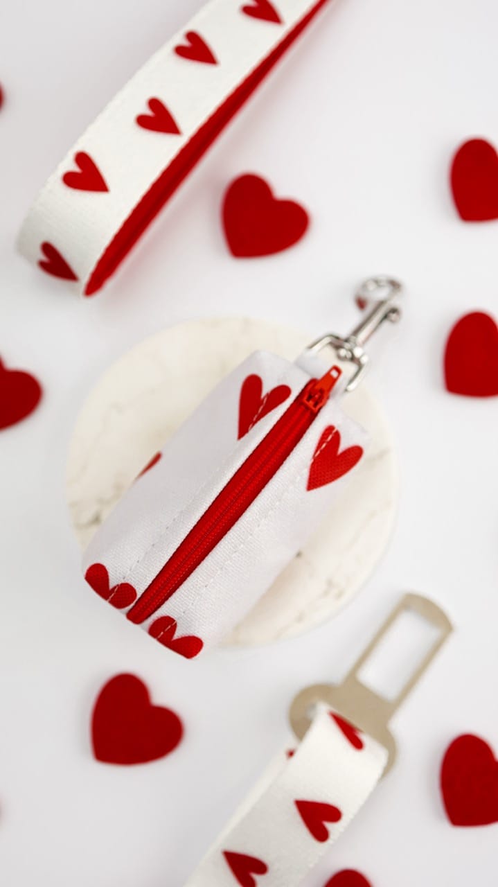 Zbliżenie na spód białego etui na kupoworki White Love, pokazujące czerwony gumowy podajnik w kształcie serca i metkę z logo Puppmour.